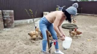 Christina feeds the chickens bare-breasted