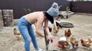 Christina feeds the chickens bare-breasted